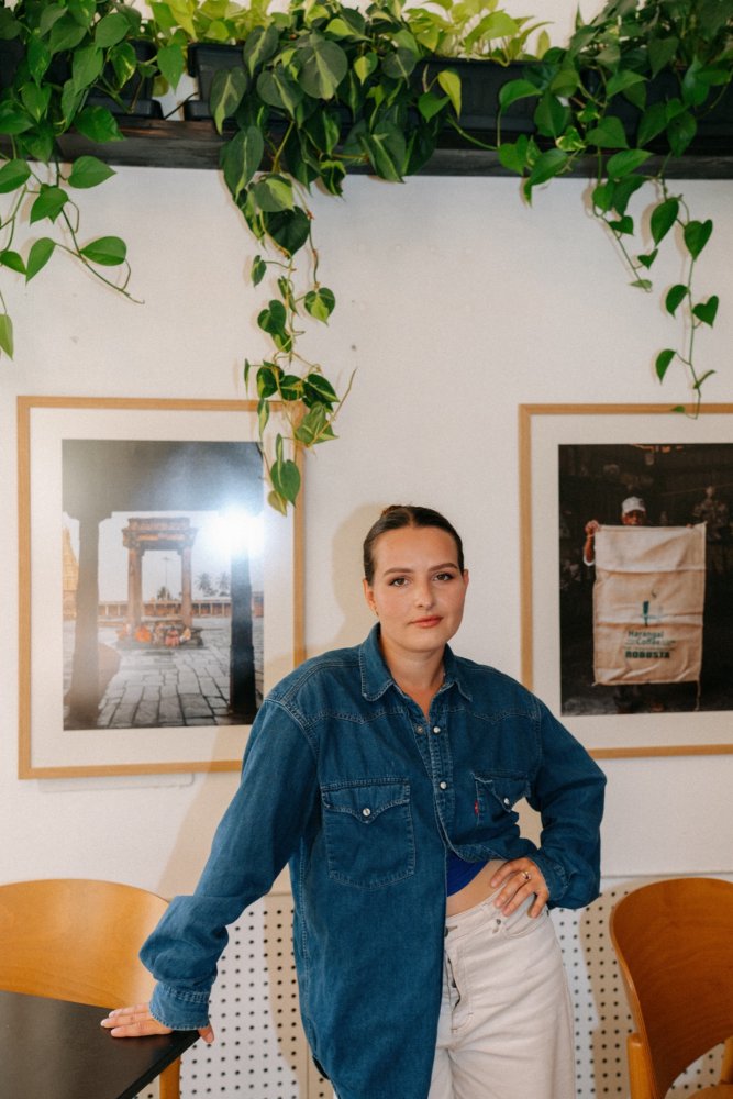 Barča Gajová stojí u svých fotek z cesty do Indie, které visí v kavárně Pikola