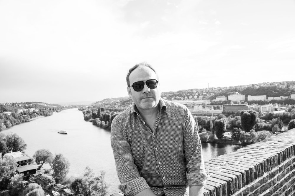 Michal Pařízek sedí na zídce a za ním je řeka a krajina